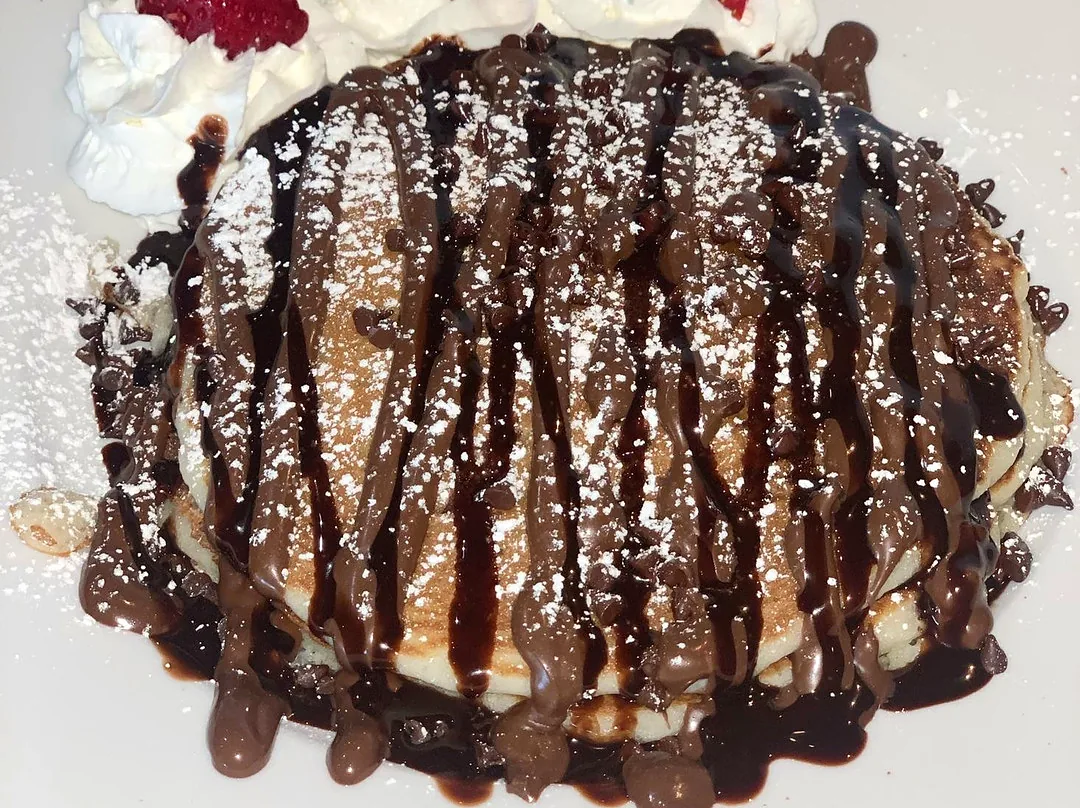 A chocolate-drizzled stack with whipped cream and strawberries